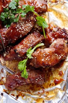 some meat is sitting on top of tin foil and garnished with cilantro