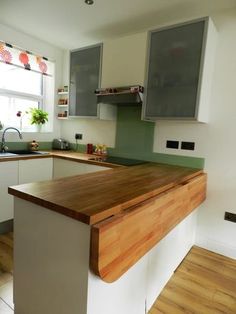 a kitchen with white cabinets and wood counter tops, along with a wooden island in the middle