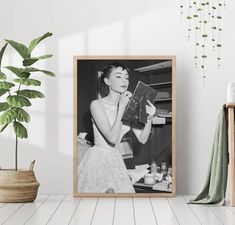 a black and white photo of a woman holding a book in front of her face