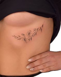 a woman's stomach with a flower tattoo on her lower side ribcage