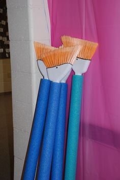 two blue and orange brushes sitting next to each other in front of a pink curtain