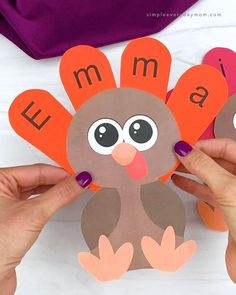 two hands holding paper turkeys with letters on them