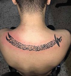 the back of a man's neck with an arabic script on his left shoulder