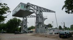 a large metal structure sitting on top of a parking lot next to a tree filled street