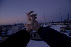 two people holding hands in front of a snowy cityscape at dusk or dawn