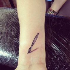 a woman's wrist tattoo with a pen on it