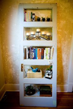 a bookshelf filled with lots of books next to a wall mounted candle holder