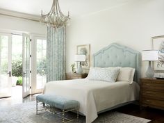 a bedroom with a bed, dresser and chandelier