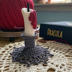 a crocheted candle holder on a doily next to a ball of yarn