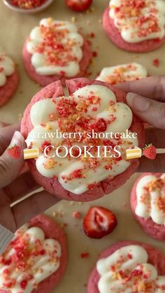 strawberry shortcakes with white frosting and sprinkles on top are being held by someone