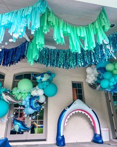 balloons and streamers are hanging from the ceiling in front of a building that has a shark theme on it