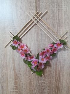 pink flowers are arranged in the shape of a heart on sticks with leaves and stems