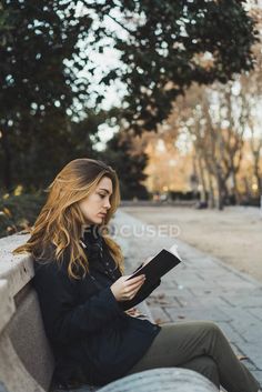 a woman sitting on a bench reading a book