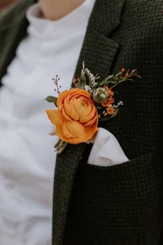 a man in a suit with an orange boutonniere on his lapel