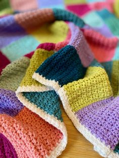 a multicolored crocheted blanket laying on top of a wooden table