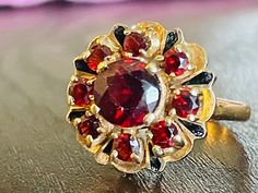 Beautiful stately antique Genuine round cut Bohemian Garnet ring set in 14k gold. There is a round cut center stone garnet measuring 6.1mm diameter and 4.1mm deep equating to 1.36 carats. The surrounding 8 round cut garnets are 2.5mm diameter for another 0.065 carats each. Total Bohemian Garnet Carat weight for this ring is nice 2.1 Carats! In between each smaller round Garnets, there are enamel painted pear shapes that are a very nice accent touch to this ring. Bohemian Garnets are amongst the Antique 14k Gold Ruby Ring With Multi-stone, Victorian Multi-stone Ruby Ring, Victorian Ruby Ring With Rose Cut Diamonds, Formal Round Garnet Cluster Ring, Victorian Ruby Ring With Center Stone, Vintage Ruby Ring With Rose Cut Diamonds, Victorian Cluster Ring With Center Stone, Heirloom Gold Cluster Ring With Garnet, Antique Yellow Gold Round Ruby Ring