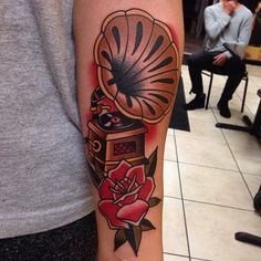 a person with a tattoo on their arm has a red rose and an old record