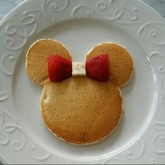 a mickey mouse pancake on a white plate with strawberries in the shape of ears