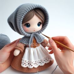 a crocheted doll is holding a knitting needle