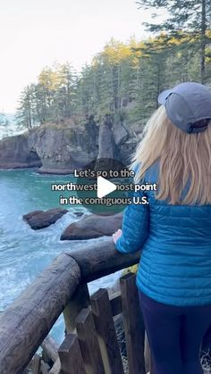 a woman looking out over the ocean from a wooden bridge with trees in the background