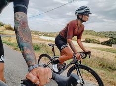 two bicyclists are riding down the road with tattoos on their arms