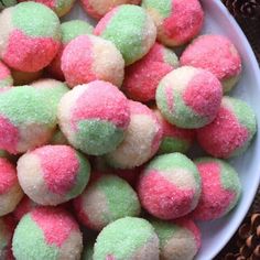 a white bowl filled with pink and green sprinkles next to pine cones