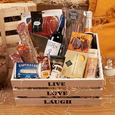 a box filled with lots of different types of food and wine bottles on top of a wooden table