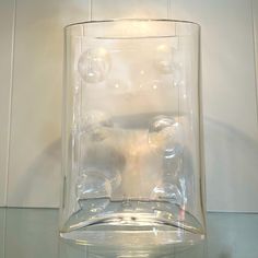 a clear glass vase sitting on top of a white counter next to a tiled wall