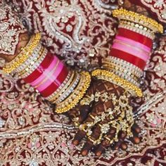 the hands and feet of a woman wearing red and gold bracelets