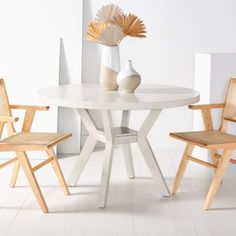 a white table with two chairs and a vase on top of it in front of a wall