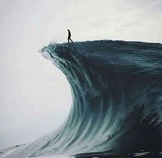 a man standing on top of a large wave in the ocean