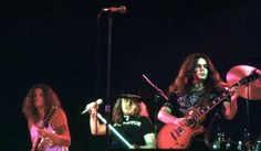 three people on stage with guitars and drums