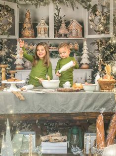 two young children sitting at a table with christmas decorations in front of them and one holding a doughnut