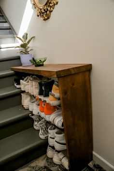 there are many pairs of shoes on the shelf next to the stair case in this room