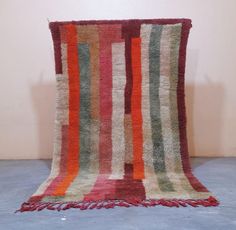 a multicolored striped rug with fringes on the floor