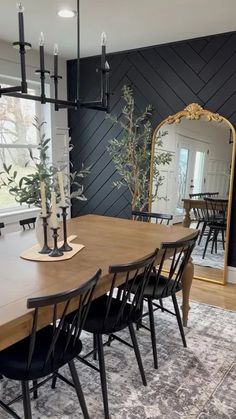 a dining room table with black chairs and a large mirror on the wall above it