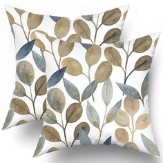 two pillows with leaves on them, one is white and the other has blue and gold