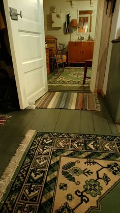 an open door leading to a hallway with rugs on the floor and furniture in the background