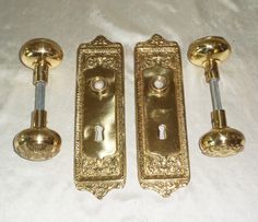 three brass door handles and knobs on a white sheet