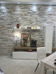 a living room with white chairs and a stone wall behind the tv stand, in front of a table