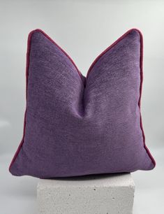 a purple pillow sitting on top of a white block