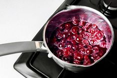 a pot filled with cherries sitting on top of a stove