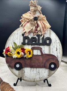 a wooden sign that says hello with a truck and sunflowers in the bed