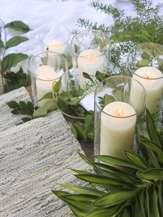 candles and greenery are arranged on the table