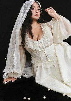 a woman in a white dress and veil with pearls around her neck posing for the camera