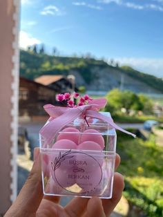 a person holding up a small box filled with pink candles