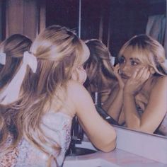 two girls looking at themselves in the mirror