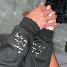 two hands with writing on them are holding each other's arms in front of a marble wall