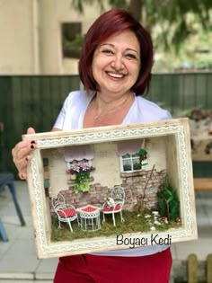 a woman is holding up a miniature house