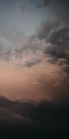 an airplane is flying high in the sky at sunset or dawn with dark clouds above it